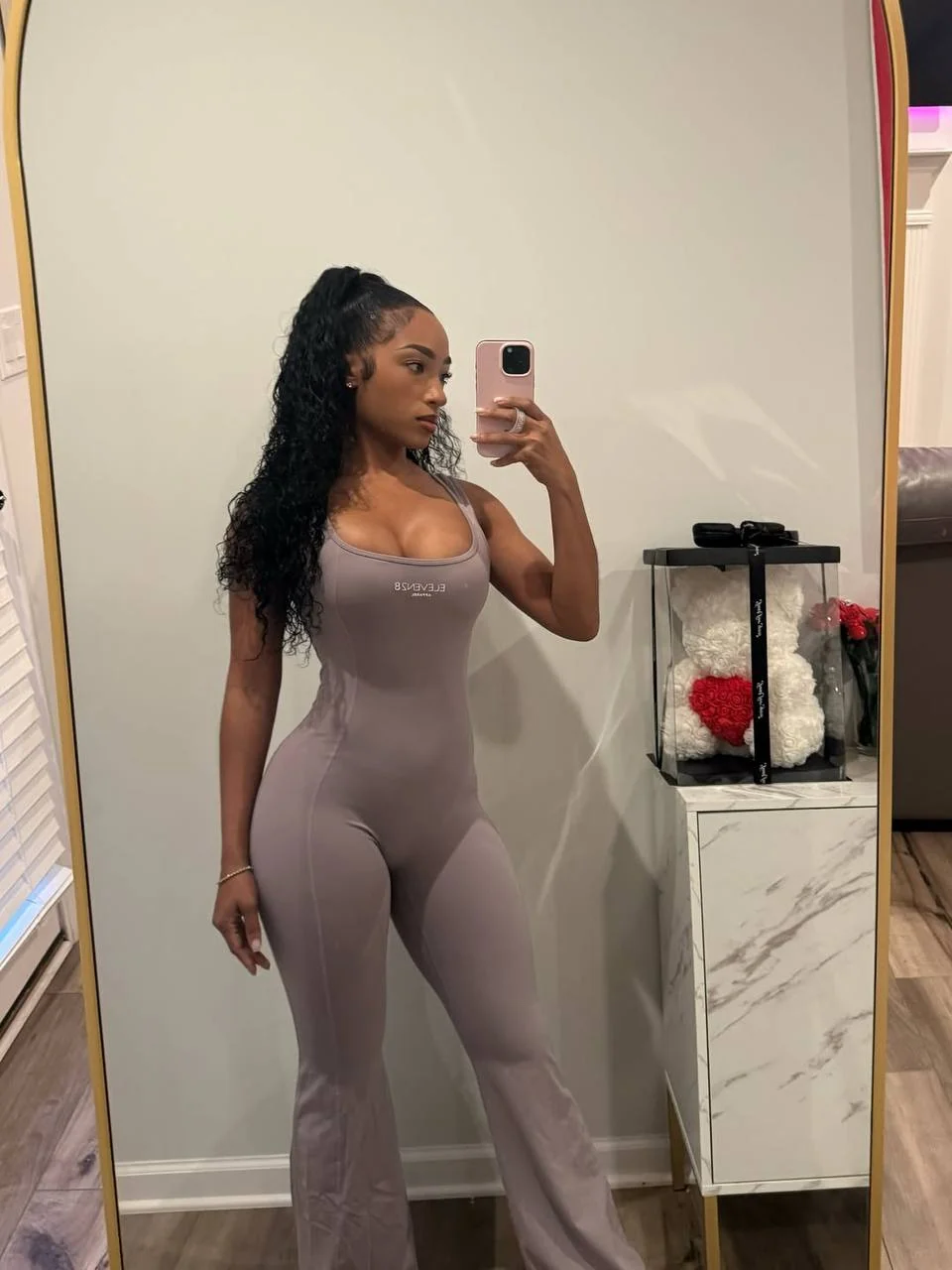 Shayla Craighead in her taupe Eleven28 jumpsuit, photographed in an arched gold mirror
